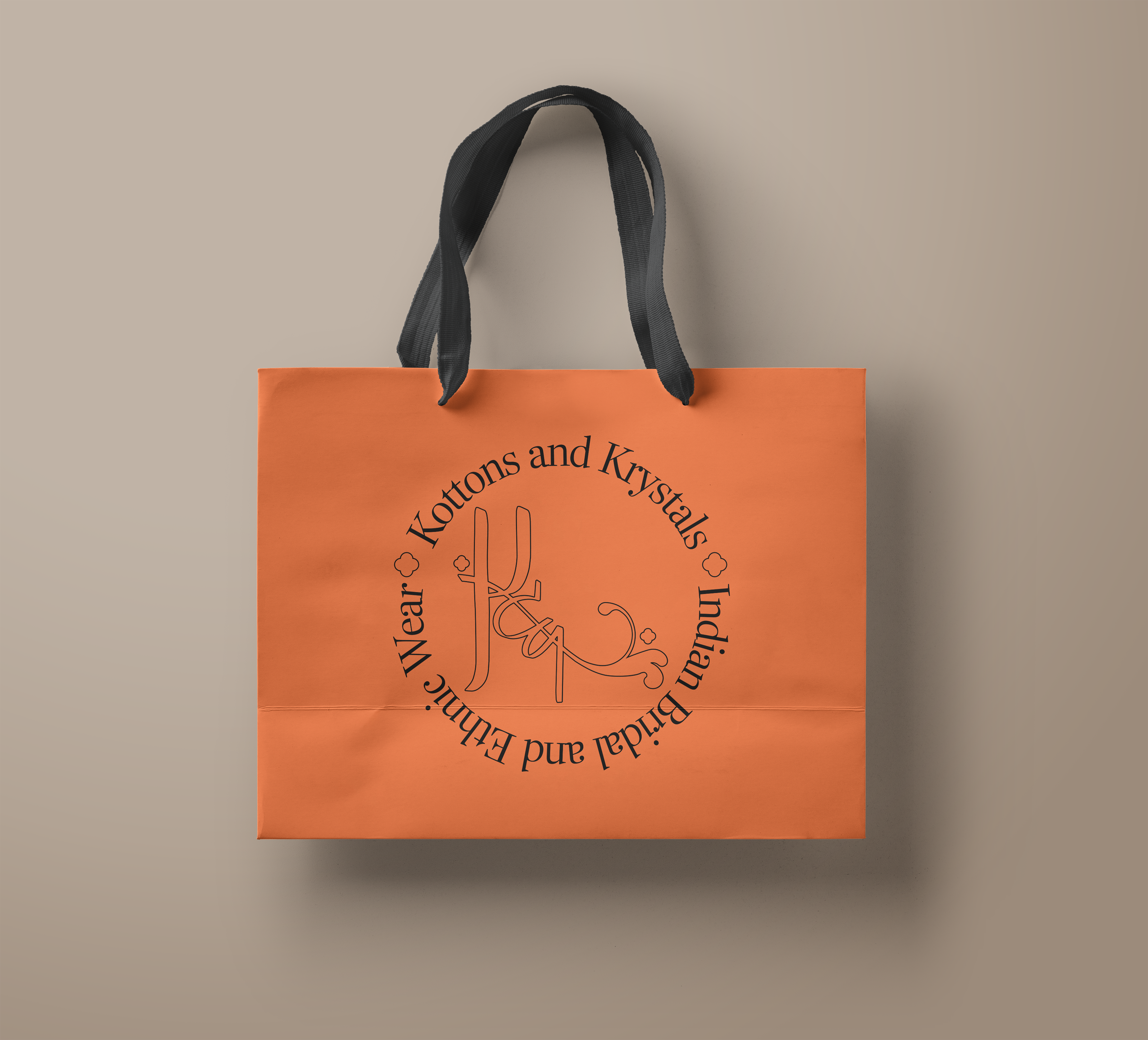 An orange shopping bag with the Kottons and Krystals logo